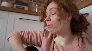 Genç beyaz kadın açgözlülükle atıştırmalık yiyor. 8K 'da kırmızı helyum kamerayla çekildi..