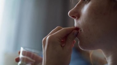 Kafkasyalı kızıl saçlı kadın hap içip su içmek üzere. 8K 'da kırmızı helyum kamerayla çekildi.. 