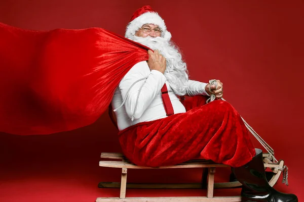 Caucasian Santa Claus with sack of Christmas Presents go of sledge