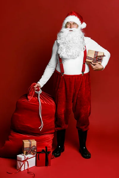 Kaukaski Święty Mikołaj Stojący Czerwonym Tle Prezentami Świątecznymi — Zdjęcie stockowe
