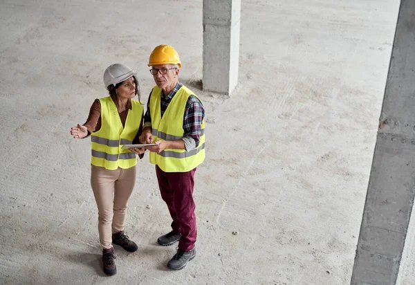 Beyaz Erkek Kadın Mühendislerin Inşaat Alanını Tartışırken Işaret Ederken Yüksek — Stok fotoğraf
