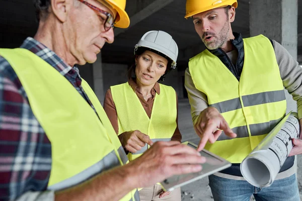 Três Engenheiros Caucasianos Discutindo Sobre Tablet Digital Canteiro Obras — Fotografia de Stock