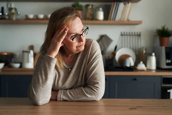 Nachdenkliche Kaukasische Seniorin Sitzt Der Küche Und Schaut Weg — Stockfoto