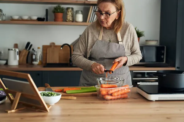 Caucásica Mujer Mayor Pelando Una Zanahoria Mientras Cocina Cocina —  Fotos de Stock