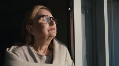 Gün batımının alevlerinde dinlenen yaşlı kadına yakın durun. 8K 'da kırmızı helyum kamerayla çekildi.   