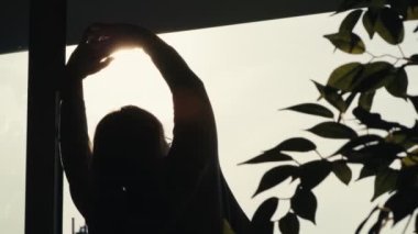 Güneş ışınlarında gerinen yaşlı bir kadının arka görüntüsü. 8K 'da kırmızı helyum kamerayla çekildi. 