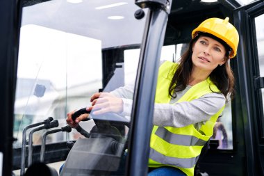 Yetişkin beyaz kadın forklift kullanıyor. 