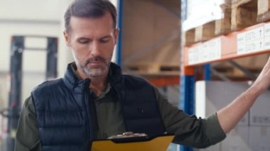 Depoda elinde belgelerle dolaşan yetişkin beyaz bir adam. 8K 'da kırmızı helyum kamerayla çekildi..  