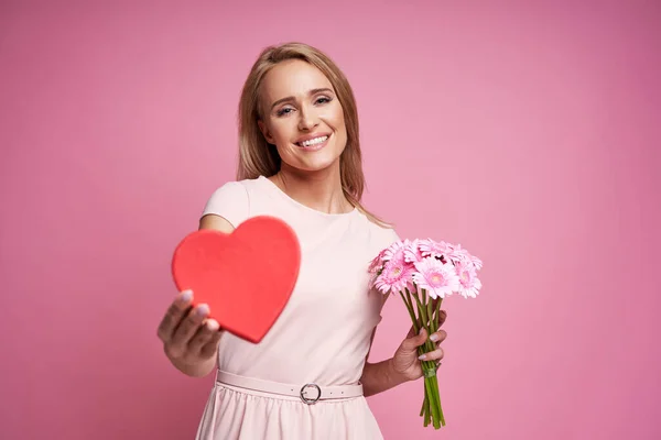 身披粉色背景 手持鲜花和木制心脏的白人女性 — 图库照片
