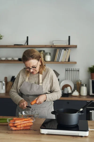 Kaukasische Seniorin Schält Beim Kochen Der Küche Eine Möhre — Stockfoto