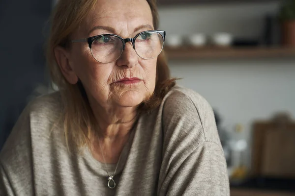 Nachdenkliche Kaukasische Seniorin Sitzt Der Küche Und Schaut Weg — Stockfoto