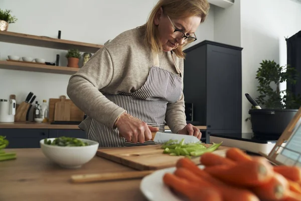 Mulher Idosa Caucasiana Cortando Legumes Enquanto Cozinha Cozinha — Fotografia de Stock