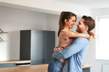 Yeni dairelerinde kucaklaşan çok heyecanlı beyaz bir çift.