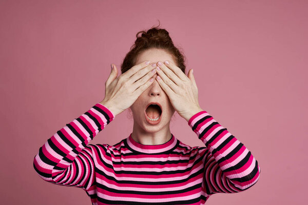 Студийный снимок молодой женщины, закрывающей глаза и кричащей 