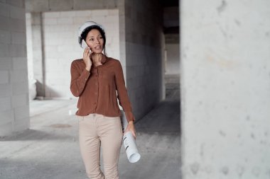 Kadın olgun Kafkas mühendisi şantiyede yürüyor.