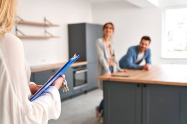 Genç beyaz çifte yeni evi gösteren emlakçı.