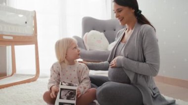 Hamileliği ilerlemiş beyaz bir kadın ilkokul kızıyla ultrason taraması yapıyor. 8K 'da kırmızı helyum kamerayla çekildi..