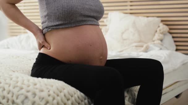 ベッドの上に座って 強い腰痛を感じる進行中の妊娠中の認識できない女性 8Kでレッドヘリウムカメラで撮影 — ストック動画