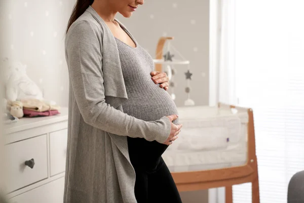 大龄孕妇站在婴儿床旁边婴儿房的侧视图 — 图库照片