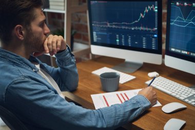 Genç, beyaz bir adam borsa verilerini takip ediyor.