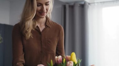 Beyaz kadın vazoya taze lale koyuyor. 8K 'da kırmızı helyum kamerayla çekildi..