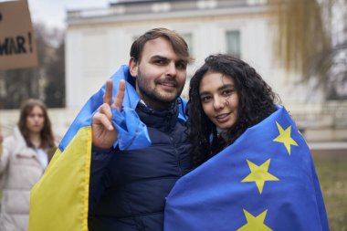 AB ve Ukrayna bayraklarıyla kaplanmış kadın ve erkek barış işareti gösteriyor 