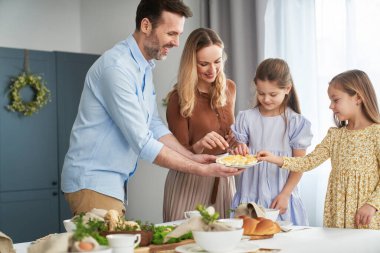 Paskalya yemeği sırasında yumurtalarla paylaşan dört kişilik neşeli beyaz bir aile.