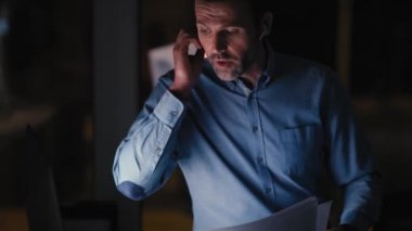 Ofiste geç saatlere kadar çalışıp cep telefonuyla konuşan beyaz iş adamı. 8K 'da kırmızı helyum kamerayla çekildi.. 