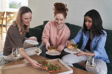 Üç beyaz bayan arkadaş tarafından yenen lezzetli pizza. 
