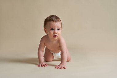 Beyaz bir bebek çıplak arka planda sürünüyor. 