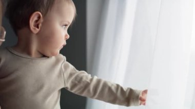 Kafkasyalı şirin bir bebeğin evdeki pencereden baktığı bir video. 8K 'da kırmızı helyum kamerayla çekildi.. 