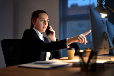 Ofiste cep telefonuyla konuşan beyaz bir kadın.