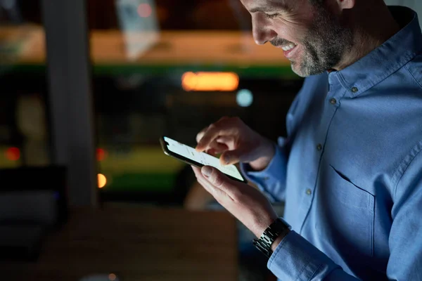 夜間にオフィスで携帯電話を使って白人男性を微笑ませる — ストック写真