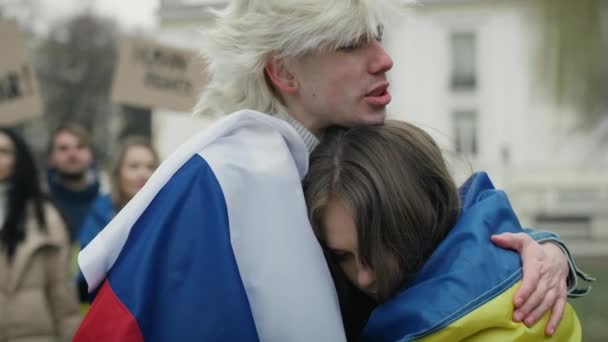 Молодой Кавказский Мужчина Российским Флагом Обнимает Молодую Кавказскую Женщину Украинским — стоковое видео