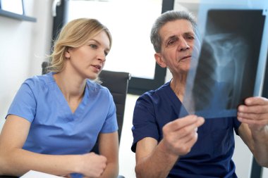 İki beyaz doktor röntgen görüntüsünü tartışıyor. 