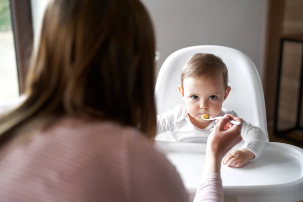 엄마가 의자에 아기에게 먹이는 — 스톡 사진