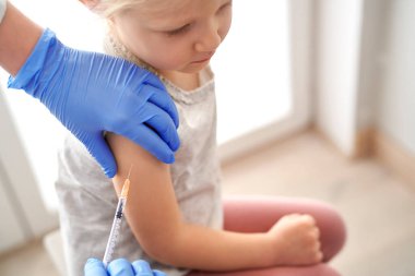 Aşı sırasında Kafkasyalı ilkokul kızının yüksek açılı görüntüsü