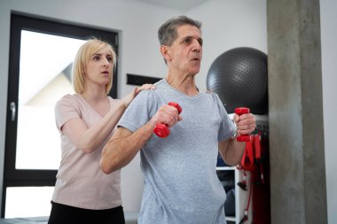 Yaşlı bir adamla çalışan kadın fizyoterapist. 