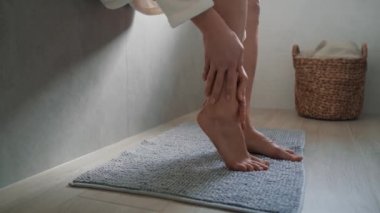 Tanımlanamayan beyaz kadın bacaklarına nemlendirici krem sürüyor. 8K 'da kırmızı helyum kamerayla çekildi..    