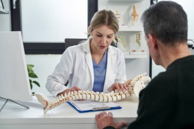 Beyaz kadın doktor hastasıyla omurgası hakkında konuşuyor. 