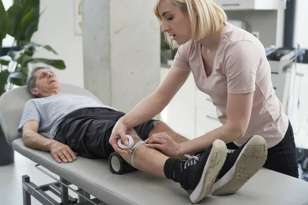 Kvinnlig Sjukgymnast Mäter Seniorns Mansben — Stockfoto