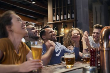 Bir grup arkadaş barda futbol maçı için tezahürat yapıyor.
