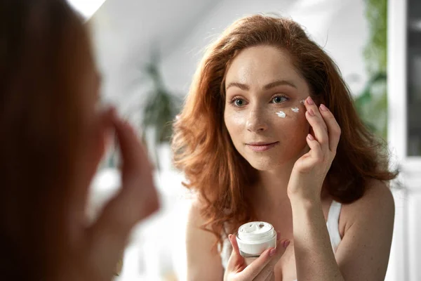 Young Caucasian Redhead Woman Smiling Applying Face Cream — Stock Photo, Image