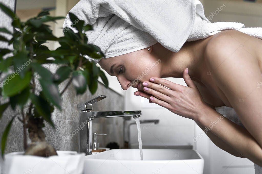 Side view of woman washing face with water in the bathroom