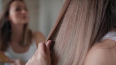 Beyaz bir kadın banyoda saç tarıyor. 8K 'da kırmızı helyum kamerayla çekildi..  