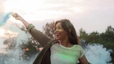 Holi Festivali 'nde renkli sis bombalarıyla dans eden çok ırklı bir kadın. 8K 'da kırmızı helyum kamerayla çekildi..