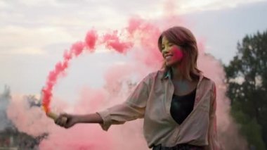 Beyaz kadın Holi Festivali 'nde renkli sis bombalarıyla dans ediyor. 8K 'da kırmızı helyum kamerayla çekildi..