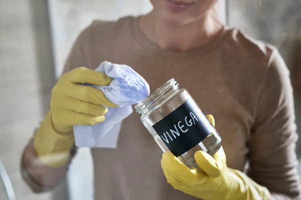 一个无法辨认的女人拿着一个装有醋和清洁床单的罐子的细节 — 图库照片