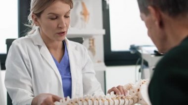 Beyaz kadın doktor hastasıyla omurgası hakkında konuşuyor. 8K 'da kırmızı helyum kamerayla çekildi.. 