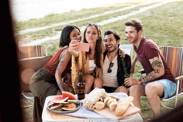 Young friends taking selfie on camping site 